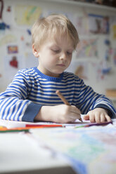 Porträt eines blonden kleinen Jungen, der mit Buntstiften malt - RBF002997