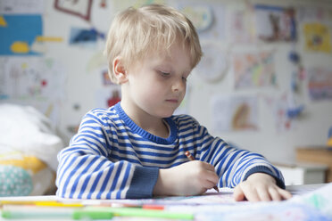 Porträt eines blonden kleinen Jungen, der mit Buntstiften malt - RBF002996