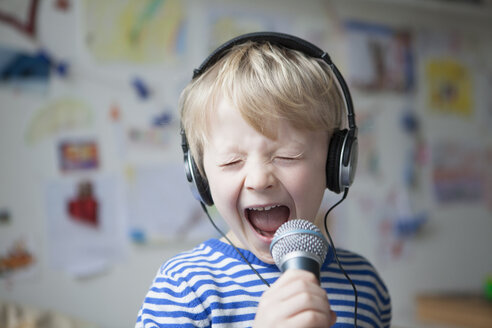 Portrait of singing little boy with headphones and microphone - RBF002990