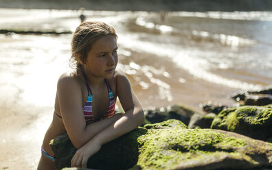 Portrait of pensive girl leaning on a rock at the beach - MGOF000599