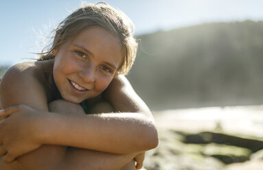 Porträt eines braungebrannten Mädchens, das am Strand sitzt - MGOF000601