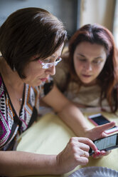 Frau hilft älterer Frau bei der Benutzung eines Smartphones - RAEF000419