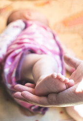 Frauenhand hält Fuß eines Babys - DEGF000515