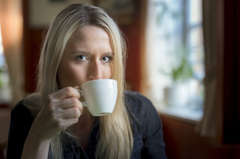 Porträt einer blonden Frau, die eine Tasse Kaffee trinkt, lizenzfreies Stockfoto