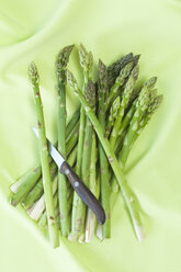 Grüner Spargel und Küchenmesser auf grünem Tuch - ASF005677