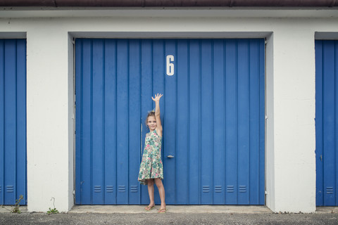 6-jähriges Mädchen vor dem Garagentor mit der Nummer 6, lizenzfreies Stockfoto