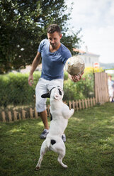 Mann mit einem Ball, der mit einer französischen Bulldogge spielt - RAEF000430