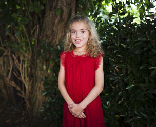 Portrait of a smiling little girl wearing a red dress - RAEF000433