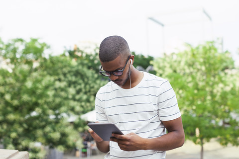 Junge afroamerikanische Studentin mit digitalem Tablet und Kopfhörern, lizenzfreies Stockfoto