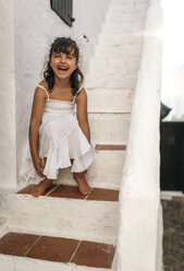 Spanien, Balearische Inseln, Menorca, Binibeca, Porträt eines lachenden kleinen Mädchens auf einer Stufe sitzend - MGOF000649