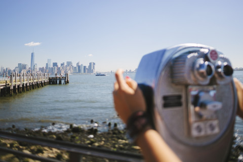 USA, New York City, Blick auf die Skyline mit einer Person, die ein münzbetriebenes Fernglas benutzt, im Vordergrund, lizenzfreies Stockfoto