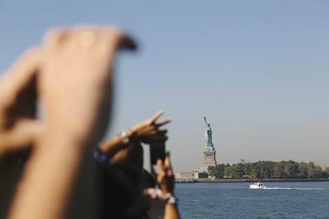 USA, New York City, Touristen beim Fotografieren der Freiheitsstatue, lizenzfreies Stockfoto