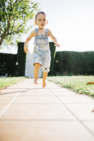 Little boy running barefoot on floor plates in the garden stock photo