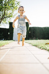 Little boy running barefoot on floor plates in the garden - JRFF000038