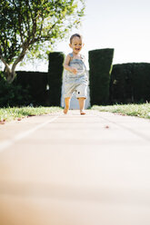 Little boy running barefoot on floor plates in the garden - JRFF000039