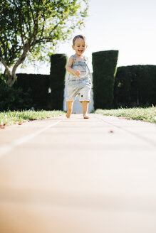 Kleiner Junge läuft barfuß auf Bodenplatten im Garten - JRFF000039