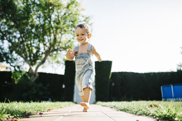 Little boy running barefoot on floor plates in the garden - JRFF000040