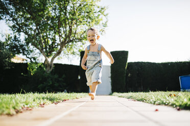 Excited little boy running barefoot on floor plates in the garden - JRFF000041