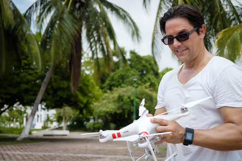 Porträt eines Mannes mit Smartwatch, der eine Drohne mit Kamera hält - ABAF001905