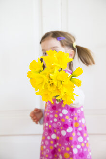 Little girl showing bunch of daffodils - LVF003779