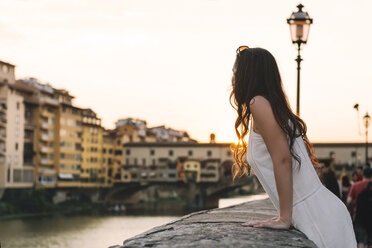 Italy, Florence, woman watching sunset behind Ponte Vecchio - GEMF000353