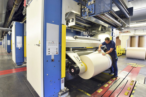 Mann arbeitet an einer Druckmaschine in einer Druckerei, lizenzfreies Stockfoto