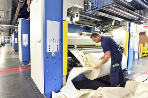 Mann arbeitet an einer Druckmaschine in einer Druckerei, lizenzfreies Stockfoto