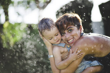 Kleiner Junge und seine Mutter genießen es, im Garten mit Wasser zu spritzen - JRFF000042