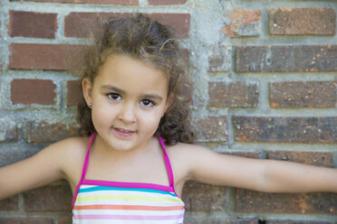 Porträt eines kleinen Mädchens, das sich an eine Backsteinmauer lehnt - ERLF000029