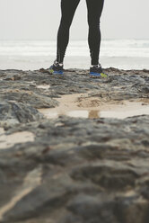 Legs of a jogger on the rocks of a beach - RAEF000472