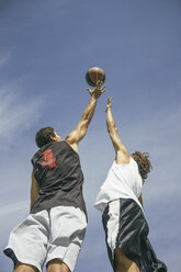 Young men playing basketball, jumping mid-air - ABZF000114