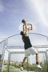 Young man playing basketball, dunking ball - ABZF000117