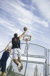Young man playing basketball, dunking ball - ABZF000115