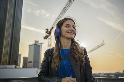 Germany, Frankfurt, smiling woman hearing music with headphones - RIBF000254