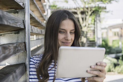 Porträt einer lächelnden Frau mit Blick auf ein Mini-Tablet - RIBF000273