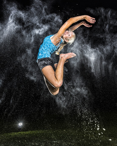 Junge Frau springt zwischen Mehlwolken in die Luft, lizenzfreies Stockfoto