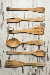 Row of six different wooden kitchen utensils on wooden background - RAEF000446