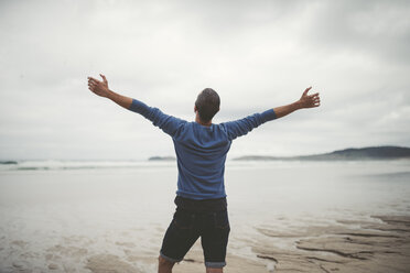 Spain, Galicia, Ferrol, man on the beach with outstretched arms - RAEF000447