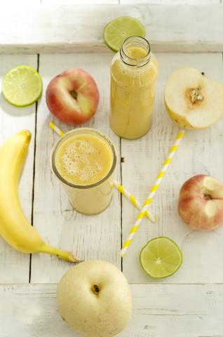 Früchte, Glasflasche und Glas mit Fruchtsmoothie auf Holz, lizenzfreies Stockfoto