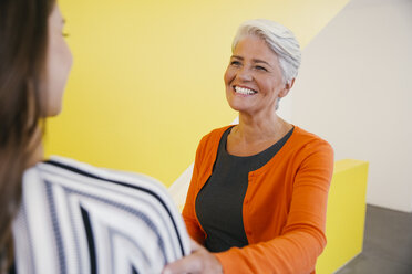 Porträt einer lächelnden reifen Frau, die eine andere Frau in einem Büro begrüßt - MFF002110