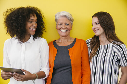 Drei lächelnde Frauen stehen vor einer gelben Wand - MFF002111