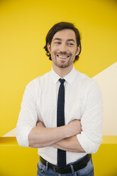 Portrait of smiling mature man wearing shirt and tie standing in front of a yellow wall - MFF002138