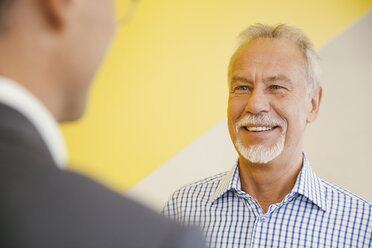 Porträt eines lächelnden älteren Mannes im Gespräch mit einem anderen Mann in einem Büro - MFF002136