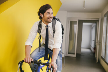 Portrait of smiling man with racing bicycle in a corridor - MFF002128