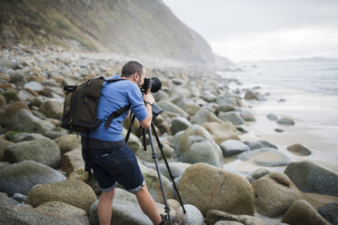 Spain, Valdovino, photographer on the beach with tripod and camera - RAEF000473