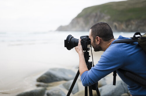 Spanien, Valdovino, Fotograf am Strand mit Stativ und Kamera - RAEF000474