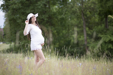 Porträt einer schwangeren Frau in weißer Kleidung auf einer Wiese - ASCF000375