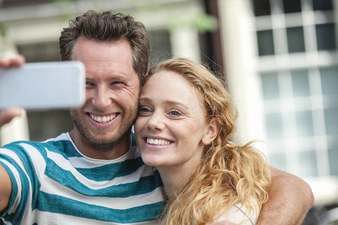 Lächelndes Paar macht ein Selfie im Freien, lizenzfreies Stockfoto