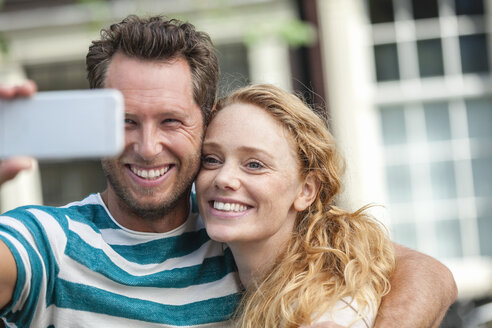 Lächelndes Paar macht ein Selfie im Freien - FMKF002095