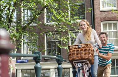 Niederlande, Amsterdam, glückliches Paar mit Fahrrad in der Stadt - FMKF002213